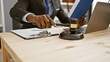 © Krakenimages.com - African american man in suit using gavel at desk with laptop in office setting conveying law, authority, and professionalism.