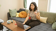 © Krakenimages.com - Hispanic woman gesturing no with finger while working on laptop at home.