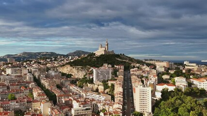 Wall Mural - Aerial shot of the city of Marseille, France at sunrise. Basilique Notre-Dame de la Garde on top of hill - landscape panorama of Europe drone view