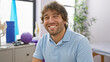 © Krakenimages.com - A smiling young caucasian man with a beard sits casually in a bright physical therapy clinic
