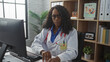 © Krakenimages.com - An african american female doctor with curly hair works at a computer in a clinic, wearing a white coat and stethoscope, emphasizing her dedication and professionalism in a medical setting.