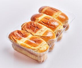 Wall Mural - Golden baked bread in clear plastic packaging isolated on a white background.