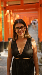 Poster - Gorgeous hispanic woman in glasses flaunting a radiant smile at the majestic torii gates of fushimi inari-taisha, kyoto