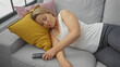 © Krakenimages.com - A young caucasian woman sleeps peacefully on a sofa with colorful pillows in a cozy living room setting.