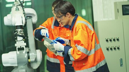 Wall Mural - Wide shot of two engineer or technician worker men with one hold tablet and discuss about robotic arm machine to check and maintenance in factory workplace.