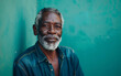 © imagineRbc - A mature African American man with grey hair and a beard is dressed in a denim shirt and poses against a teal wall