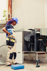 Wall Mural - Licensed mechanic looking at opened external air conditioner, puzzled about malfunctioning internal parts. African american repairman struggling to find faulty component in out of order hvac system