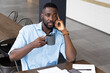 © Wavebreak Media - Holding coffee mug, man thinking while sitting at table with smartphone and papers