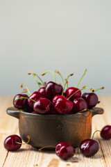 Wall Mural - ripe cherries in a clay bowl on a wooden table, close-up