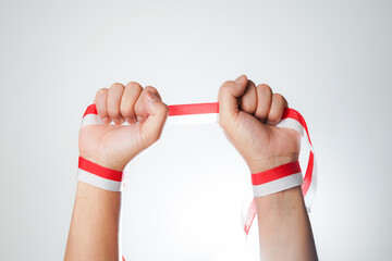 Human hand showing ribbon with the red and white color of flag. Indonesian independence day