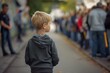 © anatolir - A little boy stands alone amidst a blurry crowd, looking away