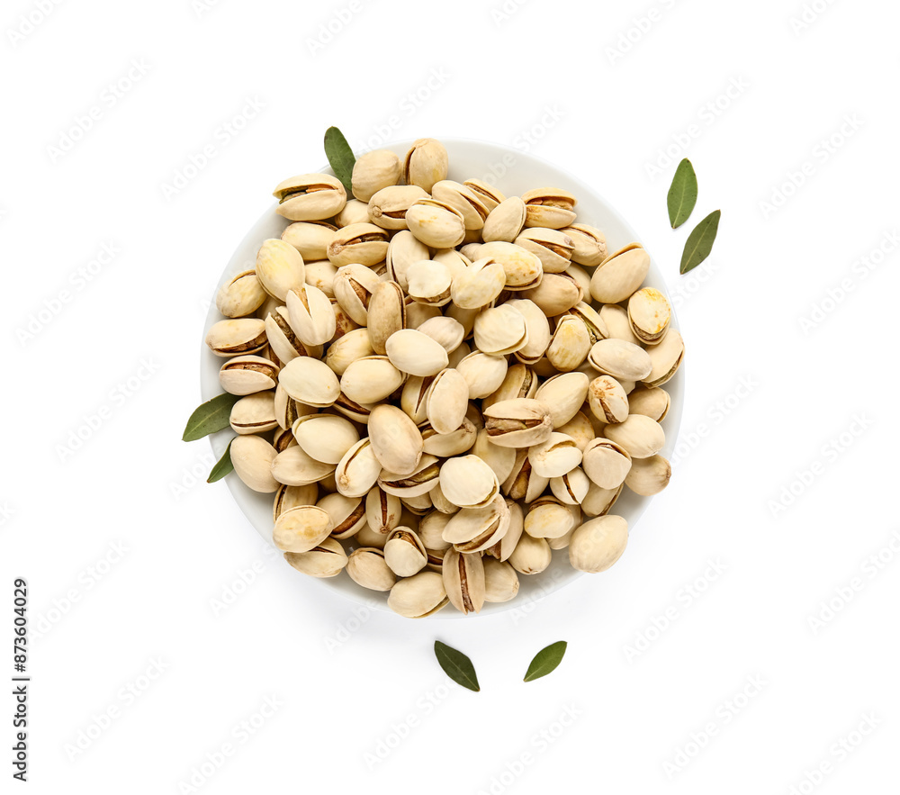 Bowl with tasty pistachio nuts and leaves on white background