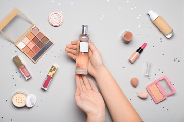 Wall Mural - Female hands with perfume bottle and different makeup products on white background