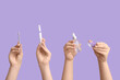 © Pixel-Shot - Female hands holding bottle and pen of cuticle oil, pusher with sea salt on lilac background