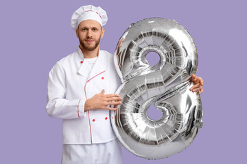 Canvas Print - Young male chef with balloon in shape of figure 8 on lilac background. International Women's Day