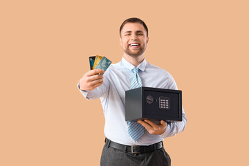 Sticker - Happy young man with safe box and credit cards on brown background