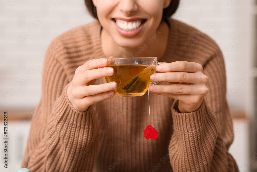 Young woman drinking hot tea in kitchen
