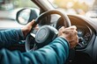 © ttonaorh - Close up of male hands on steering wheel of a car driving on the road