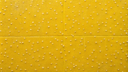 Vibrant yellow textured background with small white dots and subtle dirt specks on a glossy, smooth wall tile surface design.