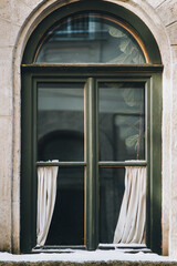 Wall Mural - Vintage green khaki window with white curtains, ficus and snow on the windowsill. Facade of a house in winter Lviv, Ukraine.