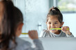 © K Davis/peopleimages.com - Girl child, mirror and brushing teeth in bathroom for hygiene with wellness, growth and gingivitis prevention in home. Young kid, reflection and tooth cleaning with development, foam and healthy gums