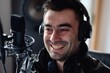 © wpw - Cheerful man wearing headphones and smiling while sitting recording a podcast or voiceover in a professional studio.