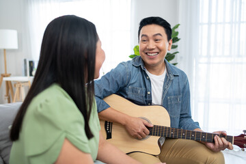 Wall Mural - Asian couple spending free leisure time together in living room in house. 