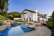 © Wirestock - luxury house with a swimming pool and patio area, surrounded by greenery and a clear evening sky.