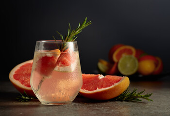 Wall Mural - Cocktail gin tonic with ice, rosemary, and grapefruit on a stone table.