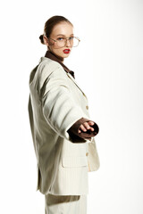 Wall Mural - A young woman with red lips and glasses poses confidently in a white suit.