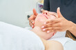 © Oscar - A woman is receiving a facial treatment from a woman. The esthetician slides her hands with oil over her neck.