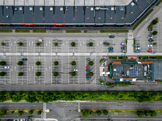 An aerial photograph captures an unoccupied parking lot, encircled by buildings and streets in an urban environment