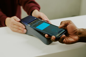 male hand holding black phone with accepted payment, female manicured hand touching payment terminal
