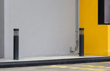 Wall Mural - Two black poles stand next to each other in front of a yellow wall