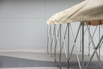 Sticker - A long, white tent with a tan cover is set up in front of a gray wall