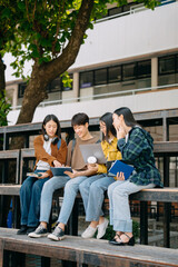 Asian Students are studying the campus park. Young people are spending time together. Reading book, working with laptop, tablet