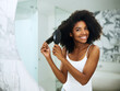 © StarDweller/peopleimages.com - Black woman, portrait and brush in mirror for haircare, daily routine and morning styling for frizz control or self care. Girl, cosmetic product and reflection in home with afro for natural hair.