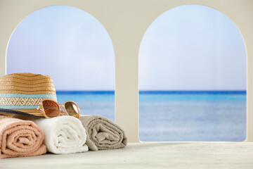 Sticker - Towels, hat and sunglasses on white furniture with tropical beach and sea background. Summer table background for montage product display.