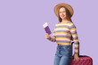 © Pixel-Shot - Smiling young woman in straw hat with suitcase, passport and ticket on lilac background. Travel concept