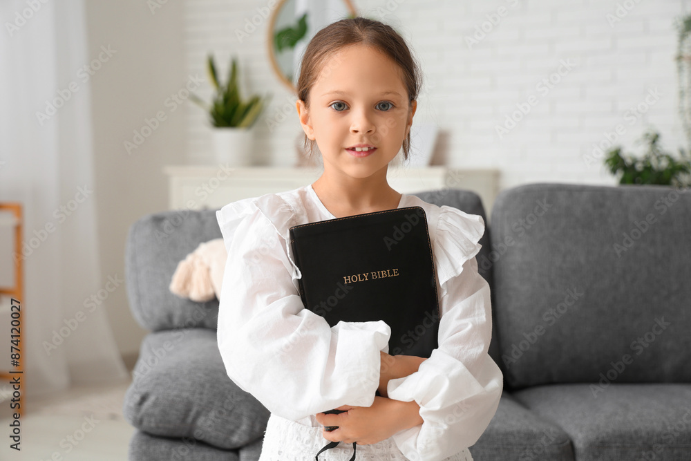 Cute little girl with Bible at home