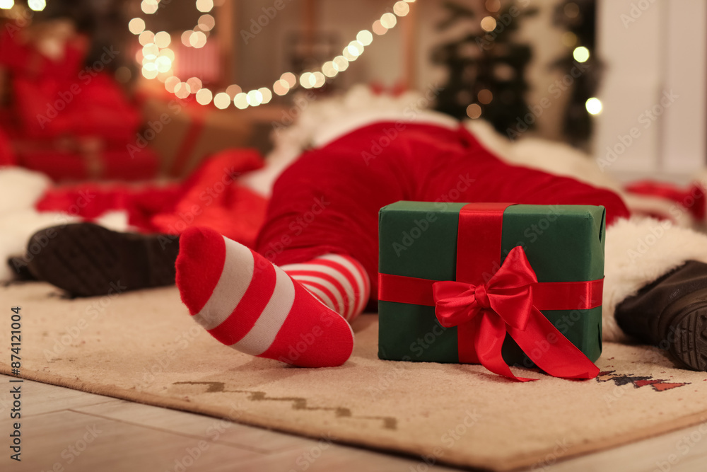 Drunk Santa Claus with gift box sleeping on carpet after party, closeup