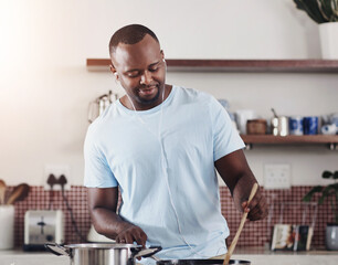 Cooking, food and music with man in kitchen of home for diet, health or nutrition recipe. Ingredients, vegetables and wooden spoon with happy African person at apartment counter for meal preparation