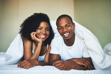 Wall Mural - Duvet, portrait and smile of couple in bedroom of home together for morning bonding or romance. Blanket, love and relax with happy African man and woman in bed for anniversary, holiday or vacation