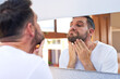 © peopleimages.com - Man, beard and mirror with morning routine in home for grooming, care and hygiene for wellness. Male person, reflection and facial hair for skincare, health and mustache growth in bathroom with pride