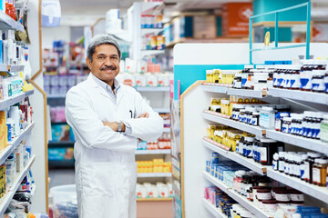 Wall Mural - Arms crossed, mature man and pharmacist at pharmacy in counter for customer service, support and help. Medical, healthcare and portrait with confidence or smile on treatment advice at drugstore