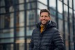 © CogniLens - Portrait of a joyful man in his 30s donning a durable down jacket in front of sophisticated corporate office background