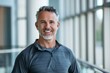 © CogniLens - Portrait of a happy man in his 40s wearing a moisture-wicking running shirt in front of sophisticated corporate office background