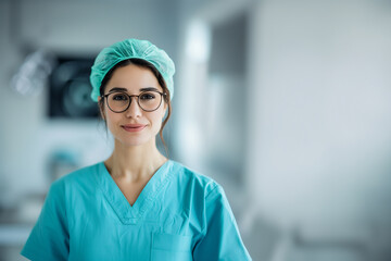 Portrait of a young female reconstructive surgeon wearing glasses and a turquoise scrub, captured in a modern medical setting, symbolizing intelligence and care.