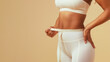 © Kiangdeb - A fit woman measuring her waist with a tape measure, showcasing a healthy lifestyle and fitness goals.