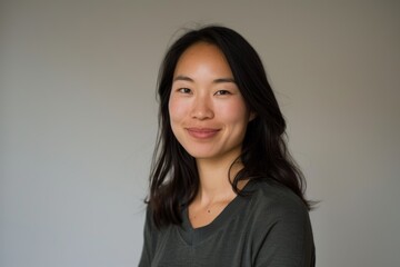 Canvas Print - Portrait of a smiling asian woman in her 30s sporting a long-sleeved thermal undershirt over minimalist or empty room background